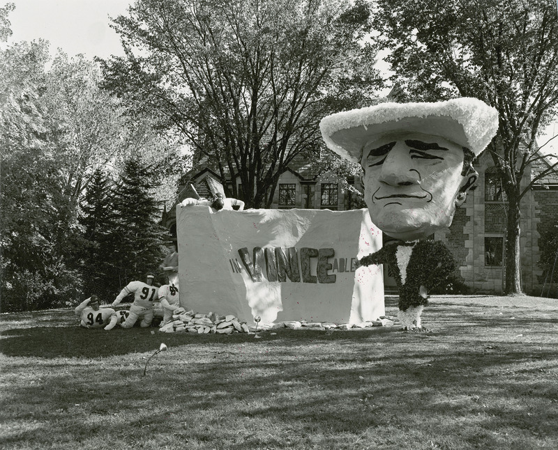 Sigma Alpha Epsilon, Iowa Gamma Chapter's lawn display features football coach Vince DiFrancesca pointing to a stone wall that says "InVINCEable." Colorado football players are attempting, with little success, to climb over or around the wall.