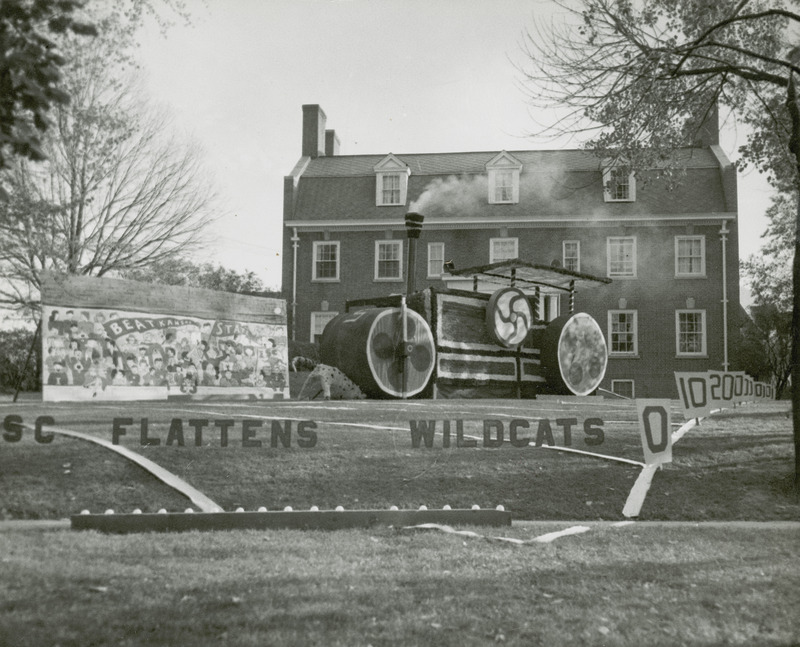 A lawn display at Sigma Nu house of a steam roller rolling over a wildcat is shown with the sign "ISC Flattens Wildcats". A large display to the left reads, "Beat Kansas State.".