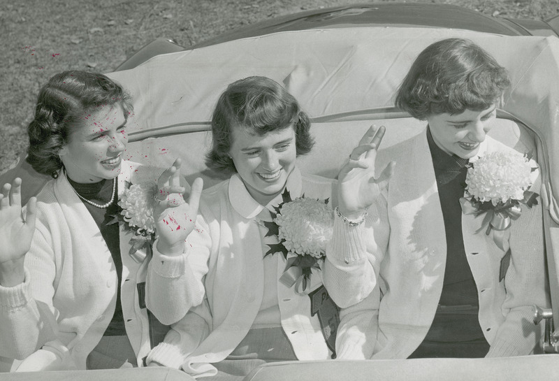 The 1951 Homecoming Queen and attendants are waving from the car. They are from left to right : Ann Bradley (Attendant); Doris Blair (Queen); and Bonnie Helfrich (Attendant).