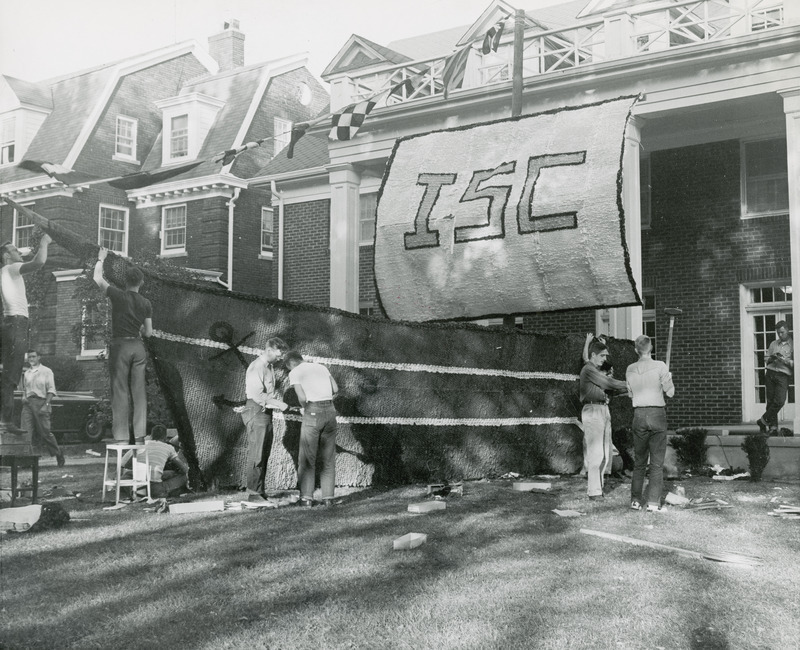 Students are working on a lawn display at the Tau Kappa Epsilon, Epsilon Chapter house. A large banner hanging above the house entrance reads, "ISC.".