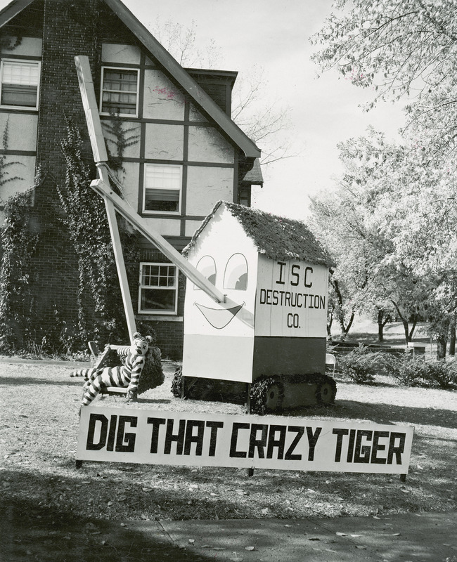 The Kappa Delta, Sigma Sigma Chapter house lawn display shows the Missouri tiger in the basket of a crane operated by the ISC Destruction Co. A sign in front reads "Dig that crazy tiger.".