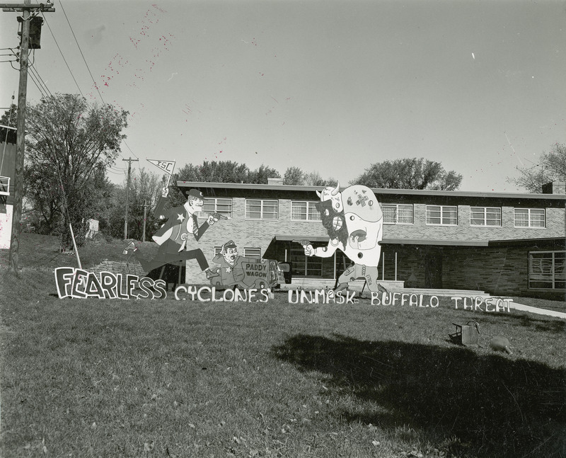 A figure reminiscent of Fearless Fosdick from the Li'l Abner comic strip runs toward a buffalo dressed in football gear. Both Fosdick and the buffalo point guns at each other.