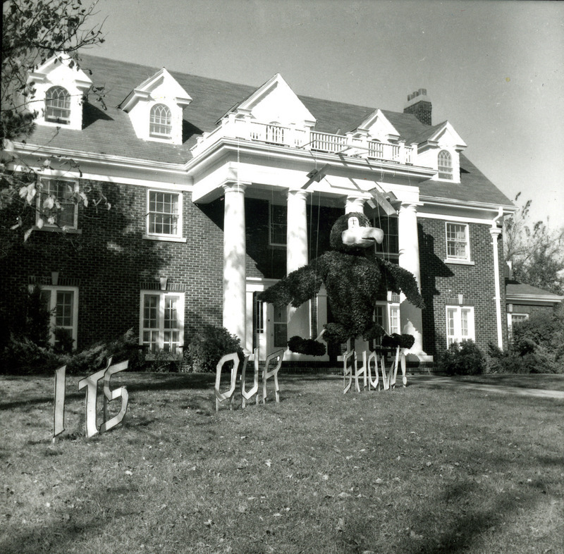 A large Kansas Jayhawk puppet is strung from the upper level of the Chi Omega, Eta Beta Chapter house. A sign on the front lawn reads, "It's our show." This display won first place in the sorority division.