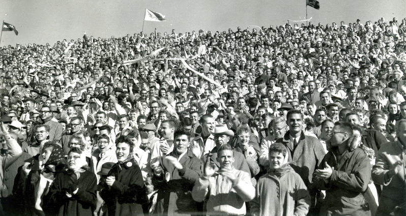 Fans wave streamers and cheer at the Homecoming football game against Kansas State University, 1959.