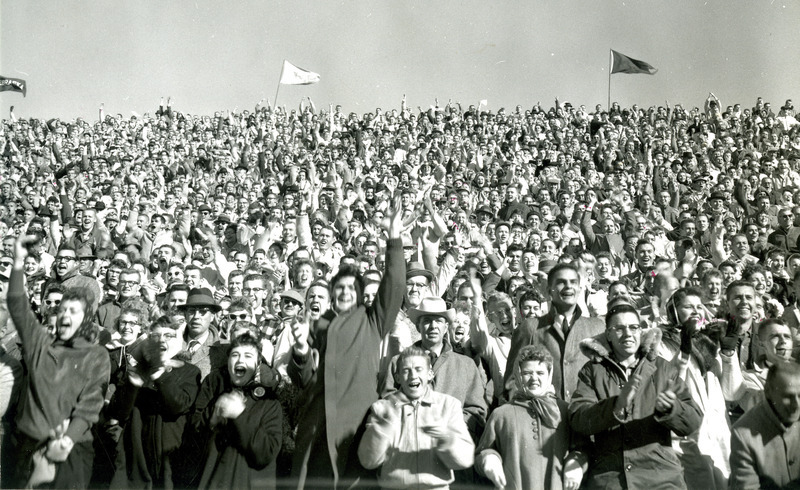 The crowd filling the stands cheers at the Homecoming football game against Kansas State University, 1959.