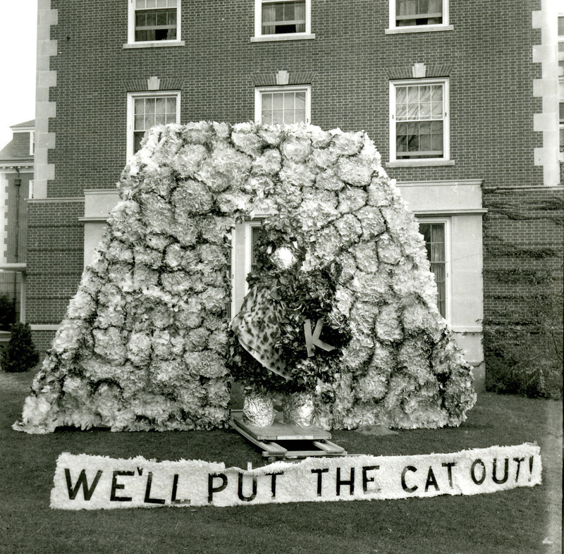 Homecoming lawn display of We'll Put the Cat Out shows Cy taking the Kansas State University Wildcat out the door of the Flintstones' cave, October 1961.