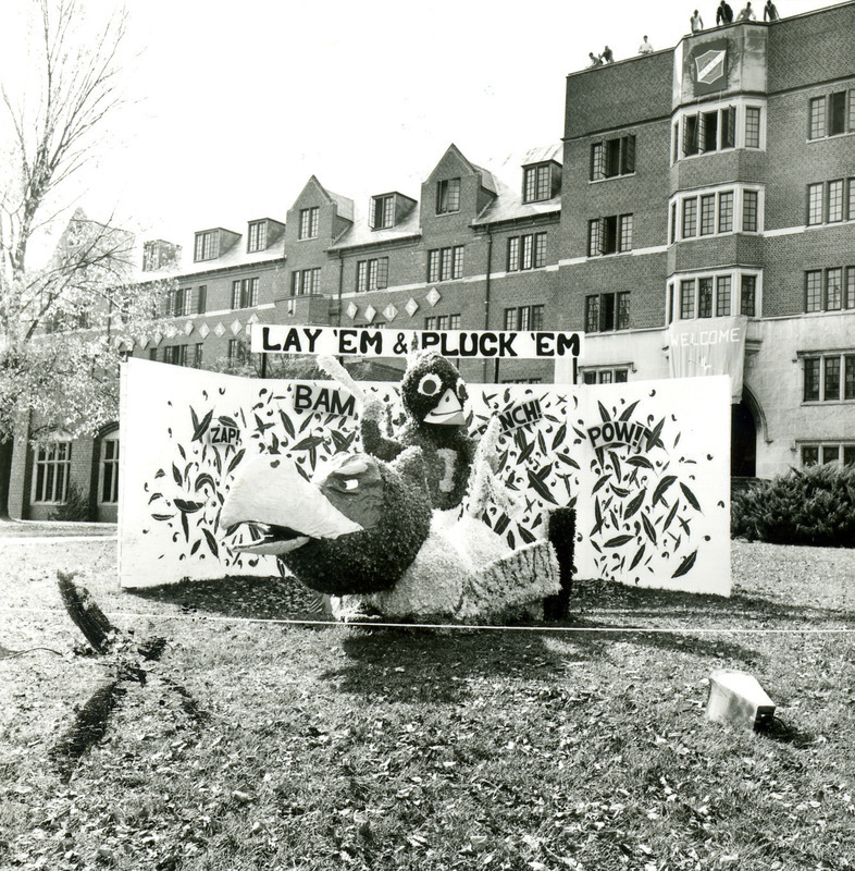 The Homecoming lawn display in front of Friley Hall of "Lay 'Em and Pluck 'Em" shows Cy treating the Kansas University Jayhawk like a chicken to be killed and plucked, 1968.