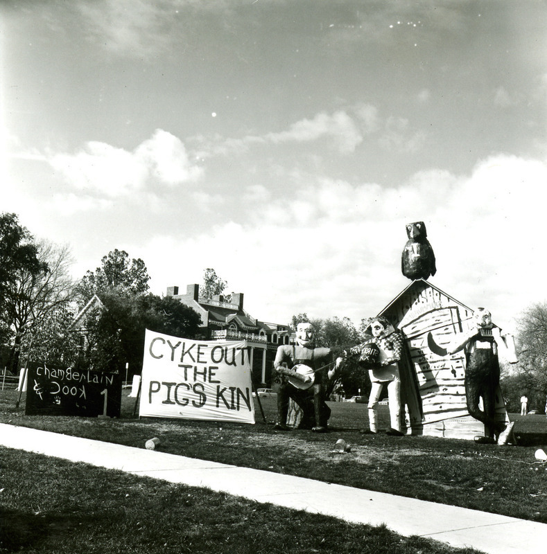 The Chamberlain House and Cook House Homecoming lawn display of "Cyke Out the Pig's Kin" shows a hillbilly band playing a banjo, jug, and harmonica, while Cy looks on from the roof of a tilted outhouse, 1968.