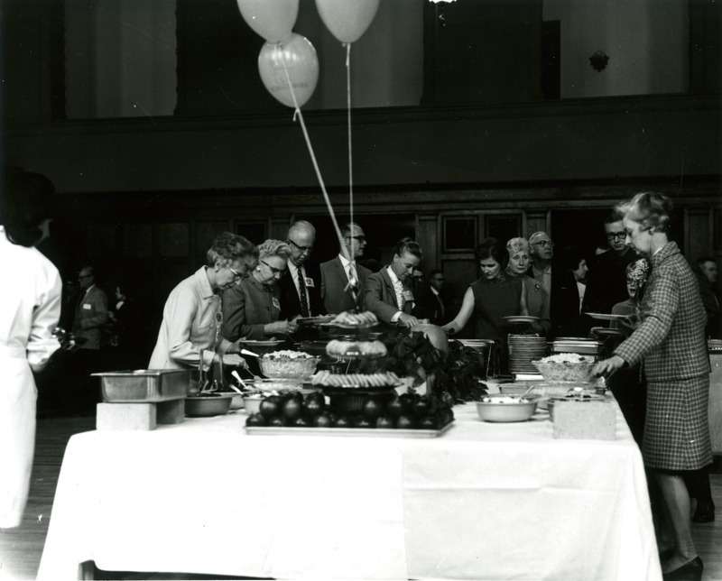 Alumni line up on both sides of a table for the Homecoming Banquet in the Memorial Union, 1969.