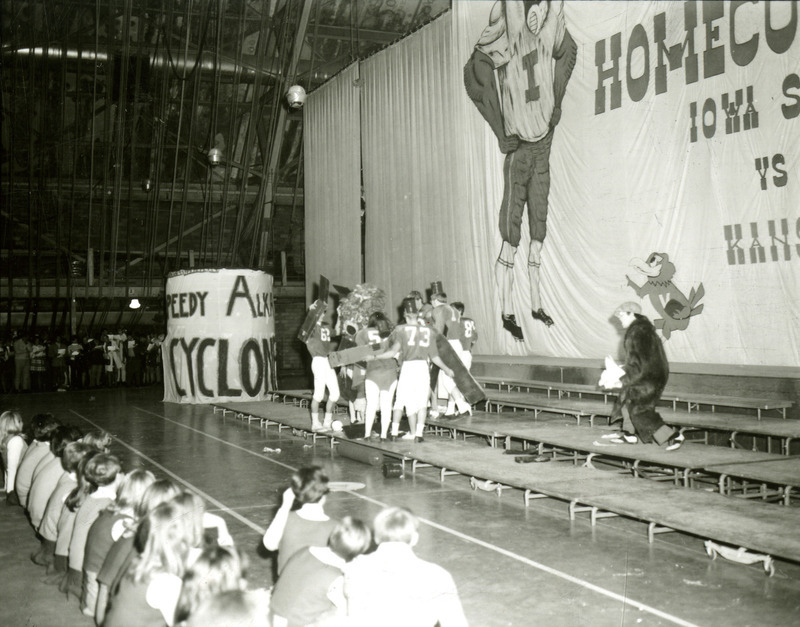 Students dressed as football players with cardboard wings and can-like hats (like flying monkeys in the Wizard of Oz?) perform a skit on the night before Homecoming, 1969. The opposing team is Kansas.