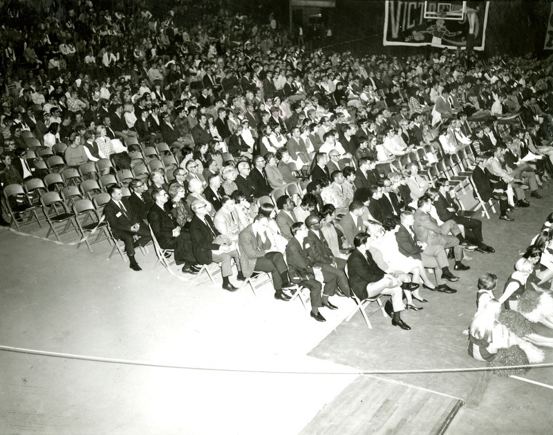 Alumni fill folding chairs behind the cheerleaders seated on the floor at the night before Homecoming Pep Rally, 1969.