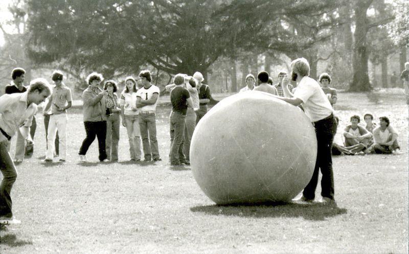 A young man leans on the push-ball as a crowd gathers in Central Campus, for a game at Homecoming, 1978.