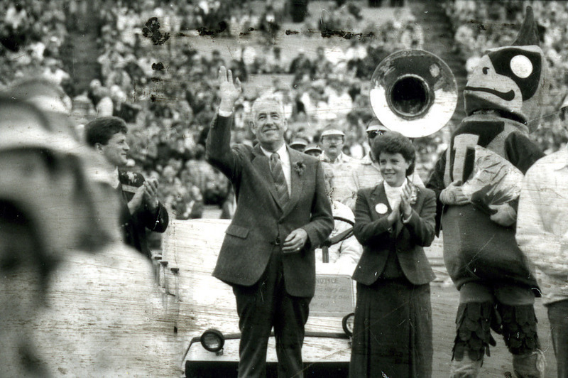 President Parks waves at Homecoming, accompanied by a woman and Cy, 1985.