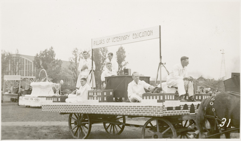 A 1937 VEISHEA parade float from the School of Veterinary Medicine. "Pillars of Veterinary Education." Six menin lab coats are positioned on this horse drawn float.