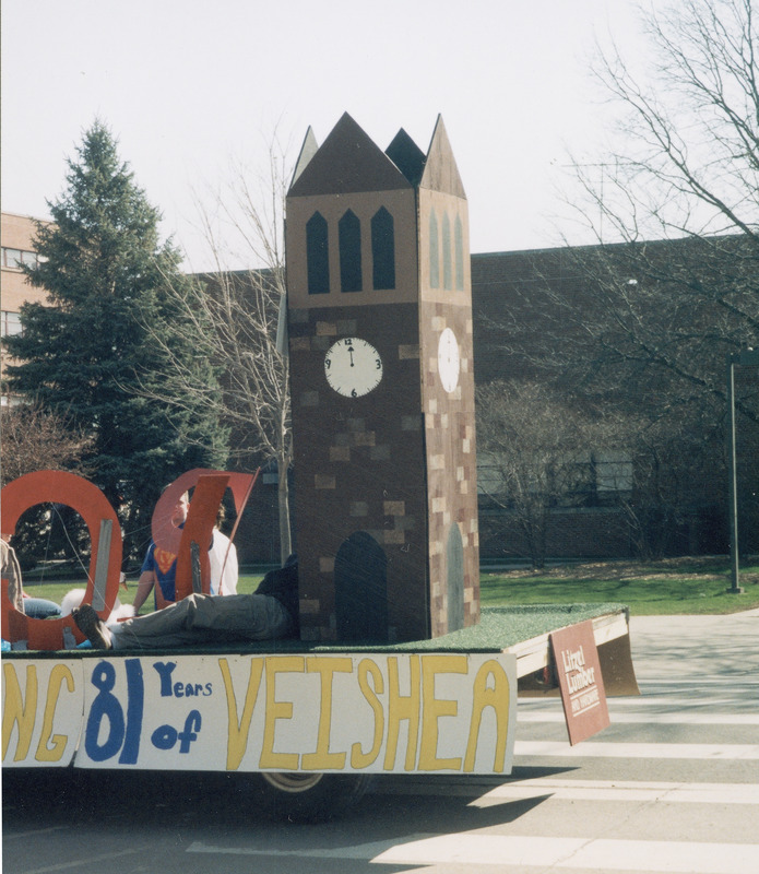 A 2003 VEISHEA parade float celebrating 81 years of VEISHEA. A student is lounging at the base of a replica of the Campanile.