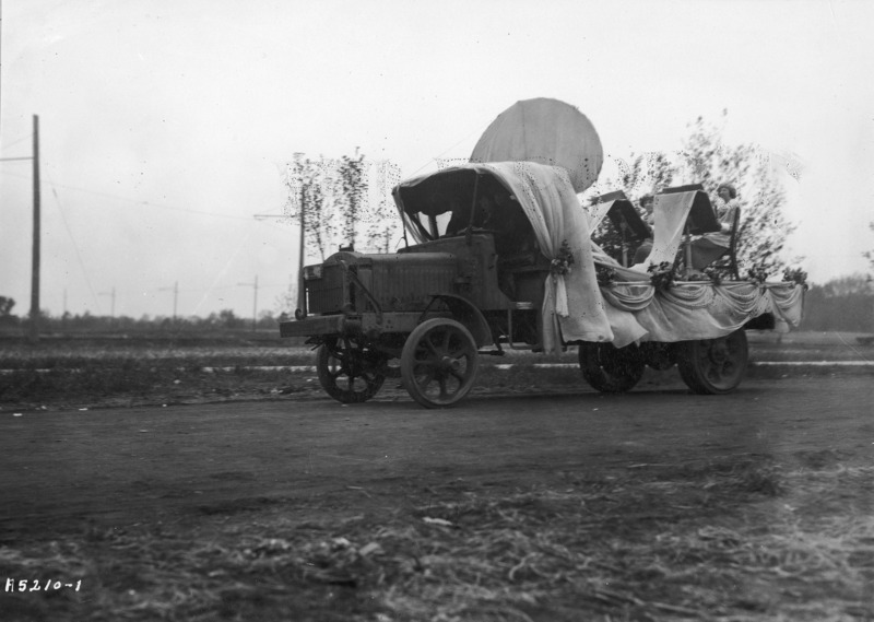 A 1923 VEISHEA float from the Department of Applied Art. One woman poses while two others in berets and smocks are painting. See photograph 1722-2-5 for another view of the same float.