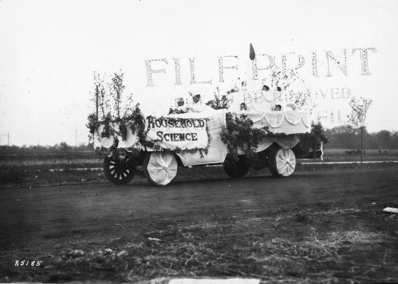 A VEISHEA Household Science float. The float, built on a flat bed truck, exhibits a giant birthday cake with one candle in celebration of the "first birthday" of VEISHEA. See photograph no. 1722-4-8 for a different view of this same float.