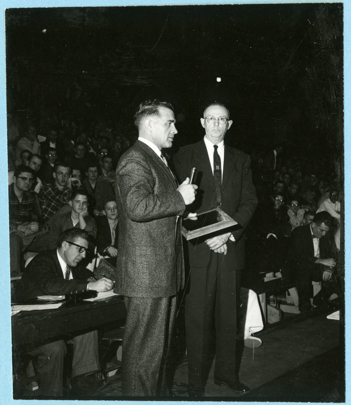 Wrestling coach Harold Nichols receives a plaque from Jess Hoke, editor and publisher of Amateur Wrestling News. The plaque names Coach Nichols the 1958 Wrestling Coach of the Year, 1959.