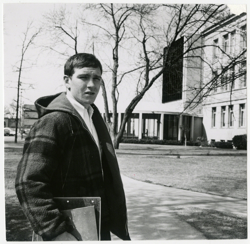 Dan Gable, Iowa State University wrestler, is standing on campus near the south entrance to the Iowa State University Library, 1970.