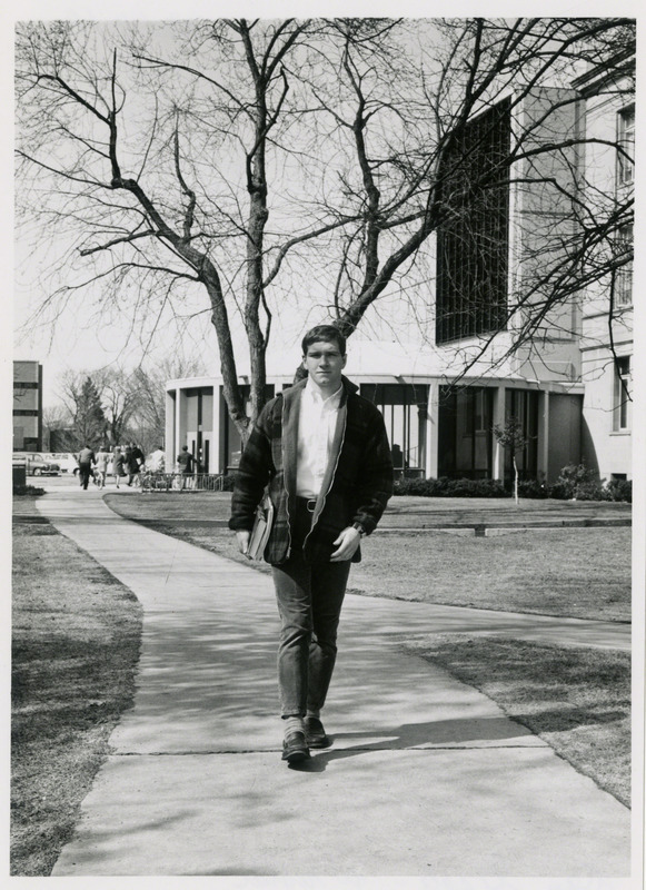 Dan Gable, Iowa State University wrestler, is walking on campus. The south entrance to the Iowa State University Library is in the background, 1970.