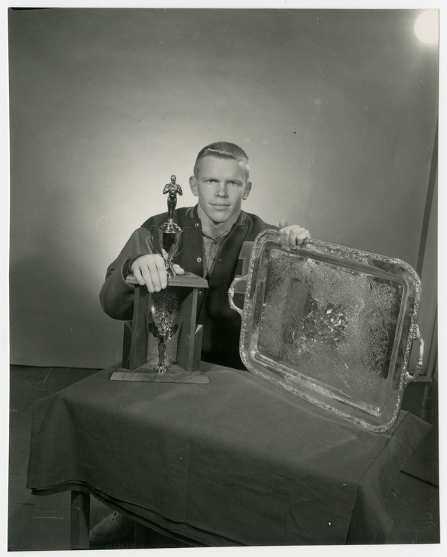 Gordon Hassman, Iowa State University wrestler, poses with a trophy, 1964.