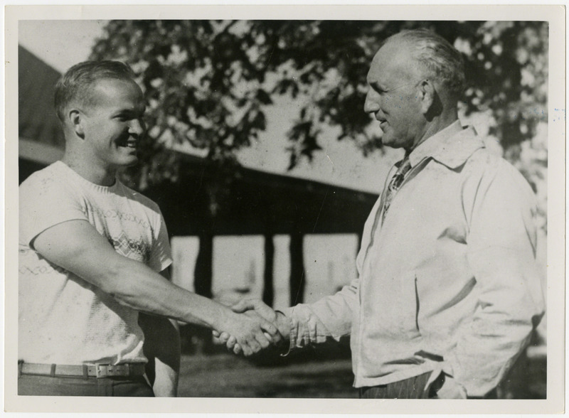 Two men shaking hands. The man on the left may be an Iowa State University wrestler.