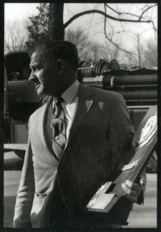 Coach Harold Nichols is holding the 1969 NCAA Champions trophy.