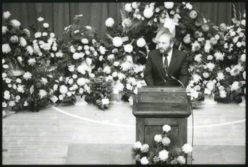 An unidentified man is speaking from the podium at the memorial service.