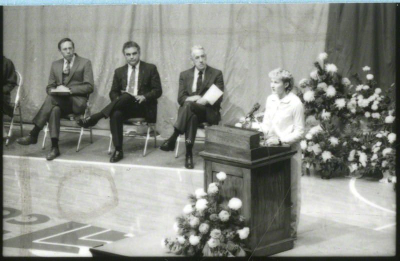 An unidentified woman is speaking from the podium at memorial service.