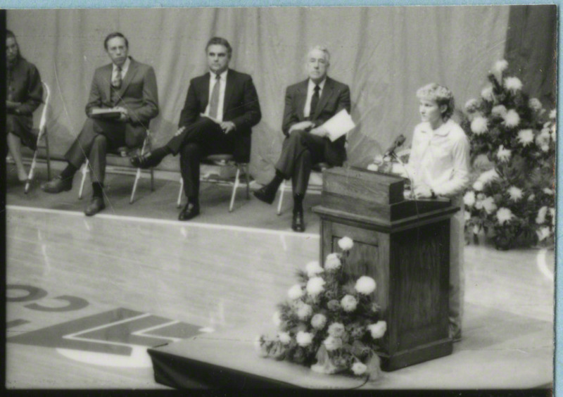 An unidentified woman is speaking from the podium at memorial service.