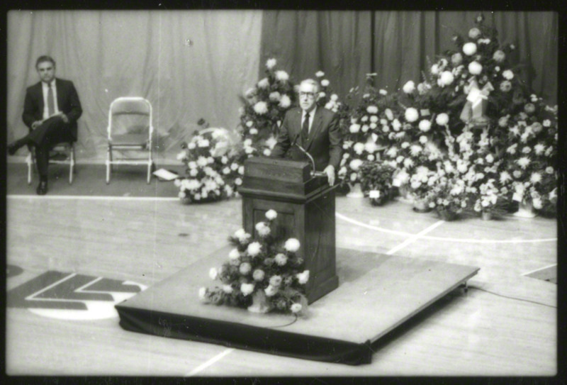 University president Dr. W. Robert Parks is speaking from the podium at the memorial service, 1985.