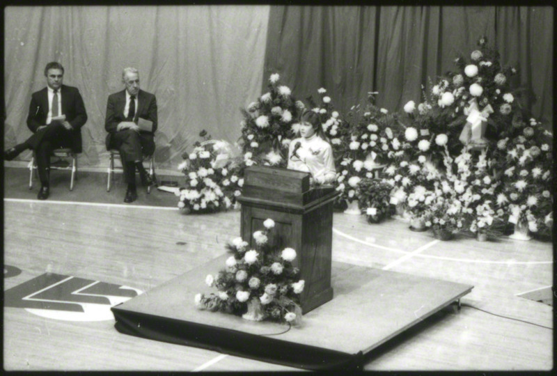 Bonnie Sons, cross-country runner, is at the podium giving a eulogy for coach Ron Renko, 1985.