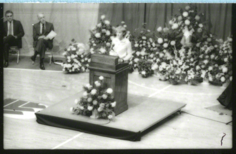 An unidentified woman is speaking from the podium at memorial service, 1985.