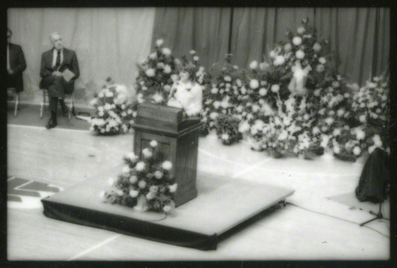 An unidentified woman is speaking from the podium at the memorial service, 1985.