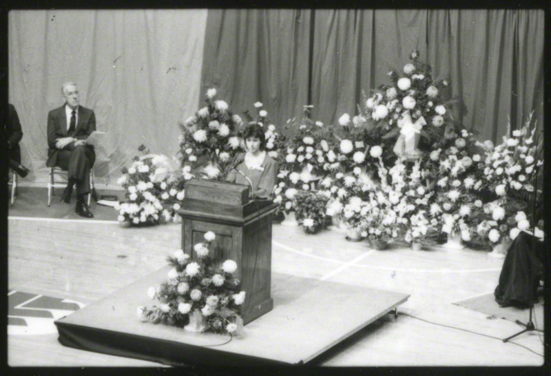 An unidentified woman is speaking at the podium, 1985.