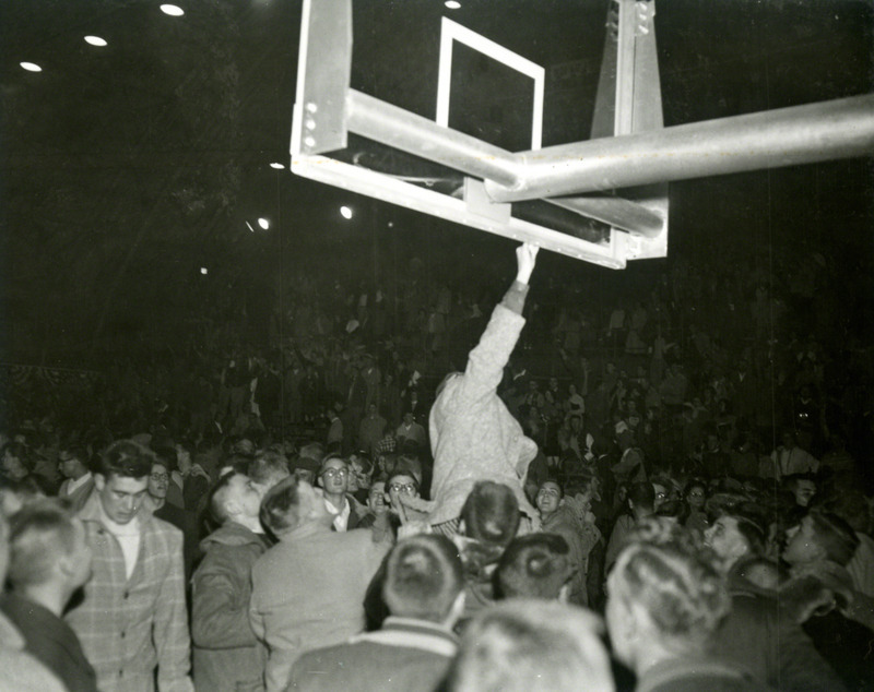 After the game, a fan jumps and touches the basketball hoop.