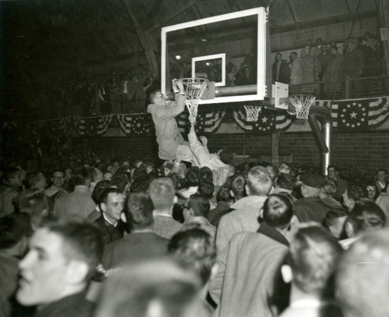 After the game, a fan jumps and hangs from the rim of the basketball hoop.