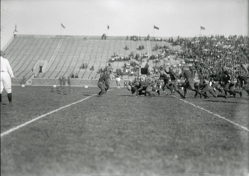 A football game being played. Spectators watch from the stands in the background.