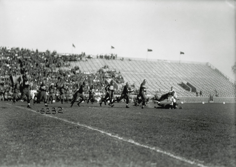 A football game being played. Spectators watch from the stands in the background.