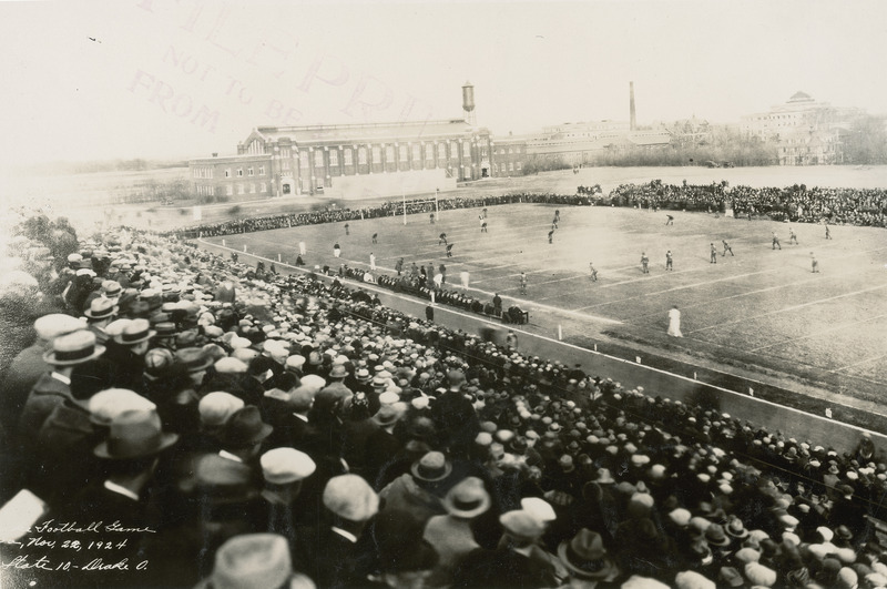 This image taken from the stands, shows the Iowa State University versus Drake University football game. The State Gymnasium and the Marston Water Tower can be seen in the background.