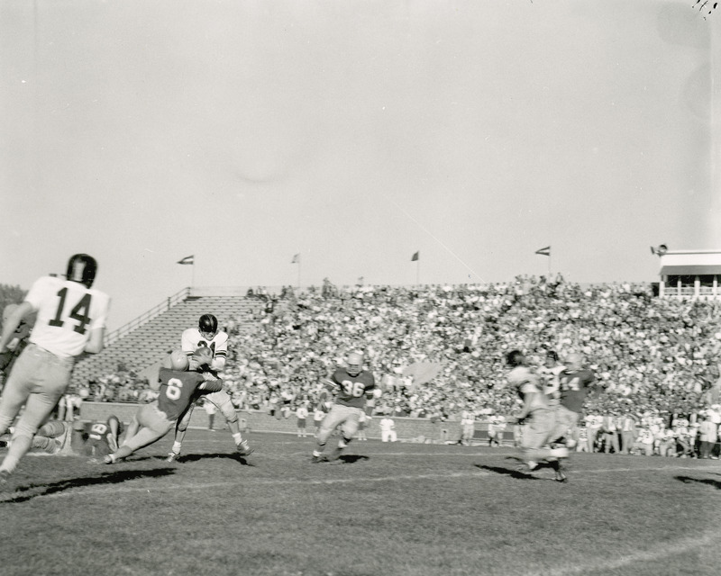 A football game in progress. Iowa State player is tackling the opponent with the ball. Spectators are in the stands.