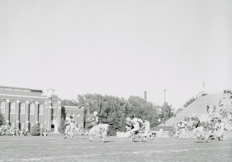 A football game in progress. One player in motion to block a pass, while an opponent is in motion to receive the pass.