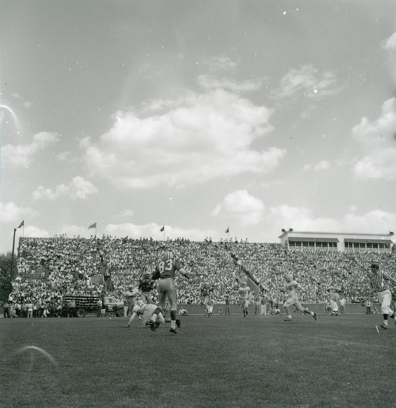 A homecoming football game in progress before a stand of spectators.