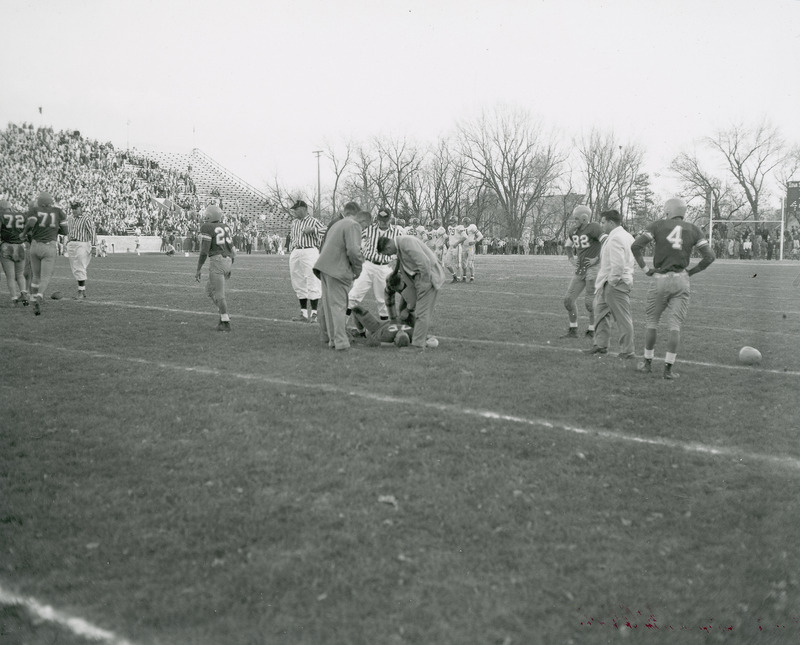 Iowa State vs. Nebraska football game. The center of the image focuses on an injured player lying on the ground surrounded by referees and other officials. Final score: ISC 7, Neb. 10.