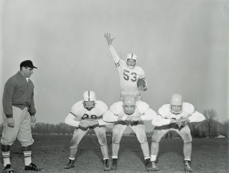 Coach Vince DiFrancesca, and football players Fred Rippel, Oliver Sparks, Ray Tweeten and Marv Walter in a posed photograph.