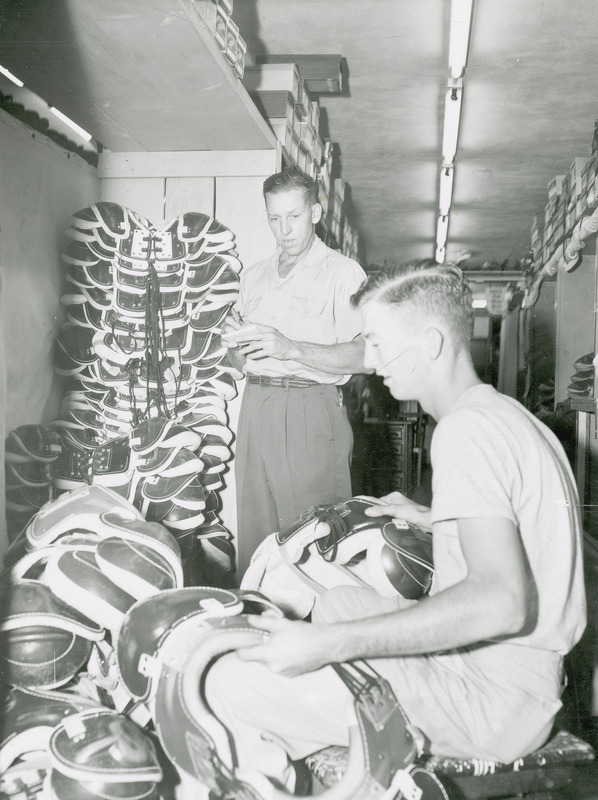 Les Askelson, equipment manager and Bill Wolfe, student football manager, examining football equipment.