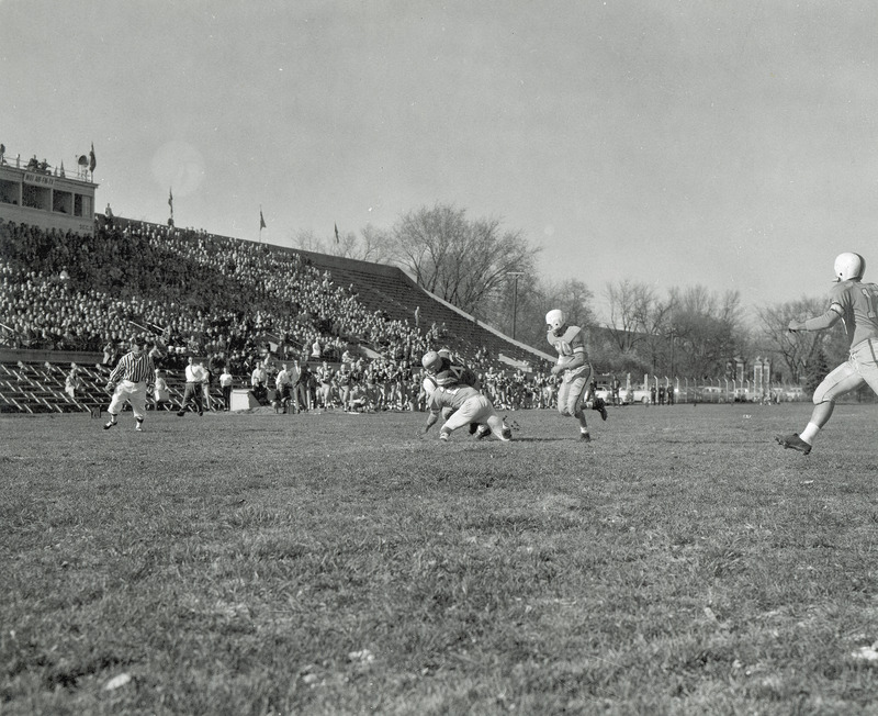 The ISC versus Drake football game in progress before a stand of spectators.