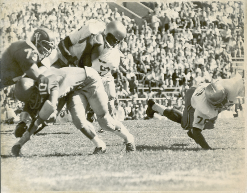 The ISU versus University of Kansas football game being played before a stadium of spectators. This game was played sometime between 1960-1974.