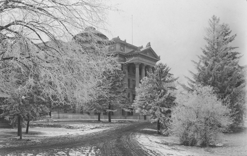 The front of Beardshear Hall from an angle.Frost on the trees and shrubs indicates it is winter. A dirt street shows tracks.