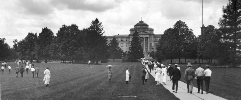 Beardshear Hall in the background of the central campus lawn, with many students on the grass and on the central walk.